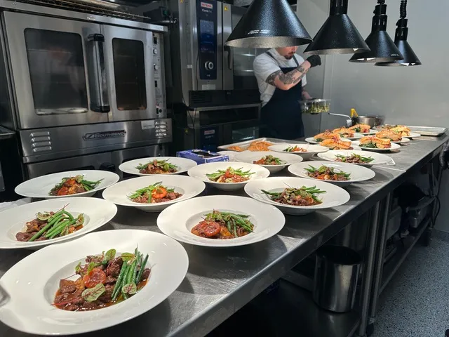 The banquet kitchen plating a course under heat lamps