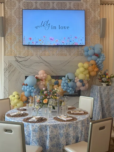 A bridal shower table set beneath a floral display