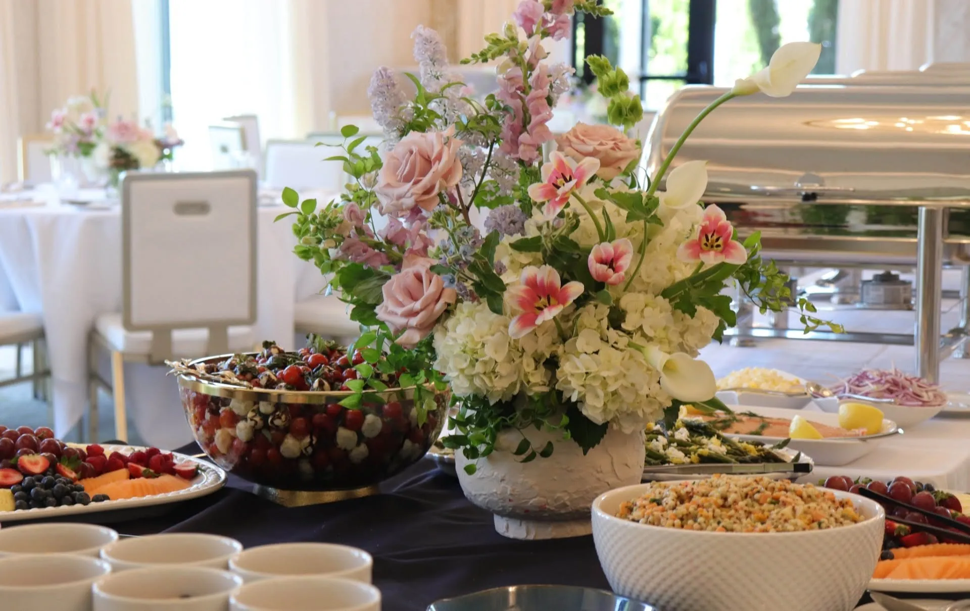 A banquet buffet laid out with spring florals in the daylit room
