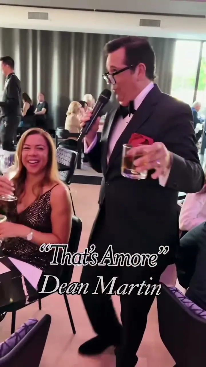 A guest raising her glass with the singer mid-chorus