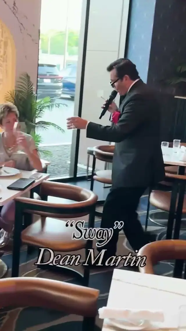 The singer toasting guests at their table by the window