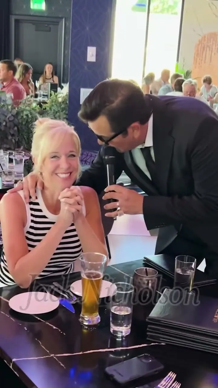 A guest laughing as the singer leans in at her table